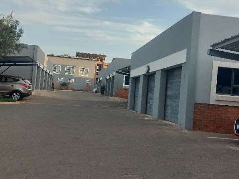 Exterior view of a residential apartment complex featuring a paved driveway and multiple garage units with modern grey finishes.