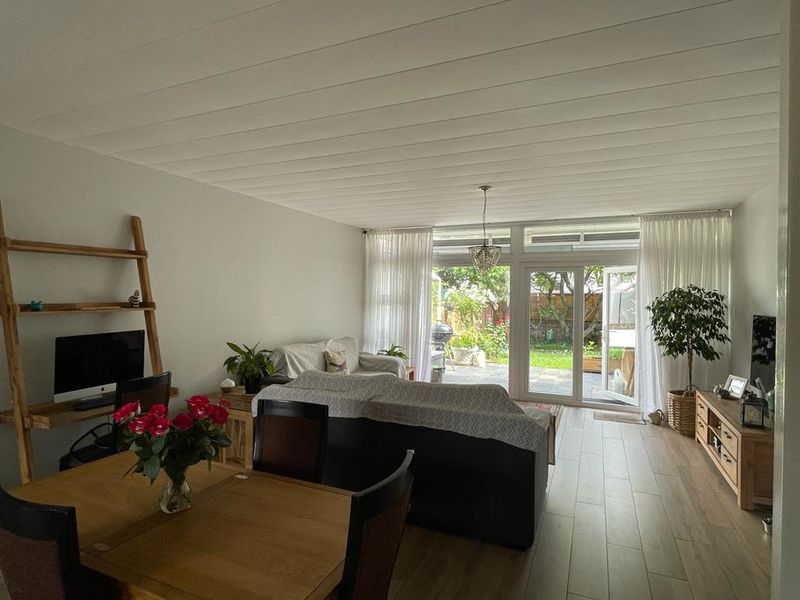 Bright and spacious living area featuring large glass doors that provide seamless access to the outdoor patio and garden.