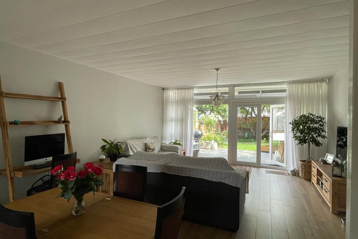 Bright and spacious living area featuring large glass doors that provide seamless access to the outdoor patio and garden.