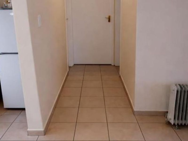 A clean and functional hallway featuring neutral tiled flooring and access to adjacent rooms through standard internal doors.