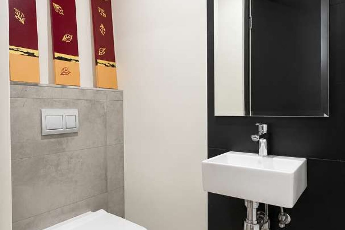 Modern guest bathroom featuring a wall-mounted toilet with concealed cistern, sleek wall-mounted basin, and contemporary black tiled feature wall.