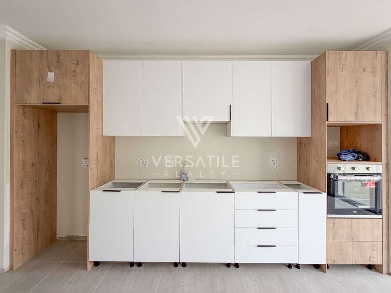 A modern kitchen area featuring two-tone cabinetry and a built-in oven, currently awaiting countertop installation and final finishing touches.