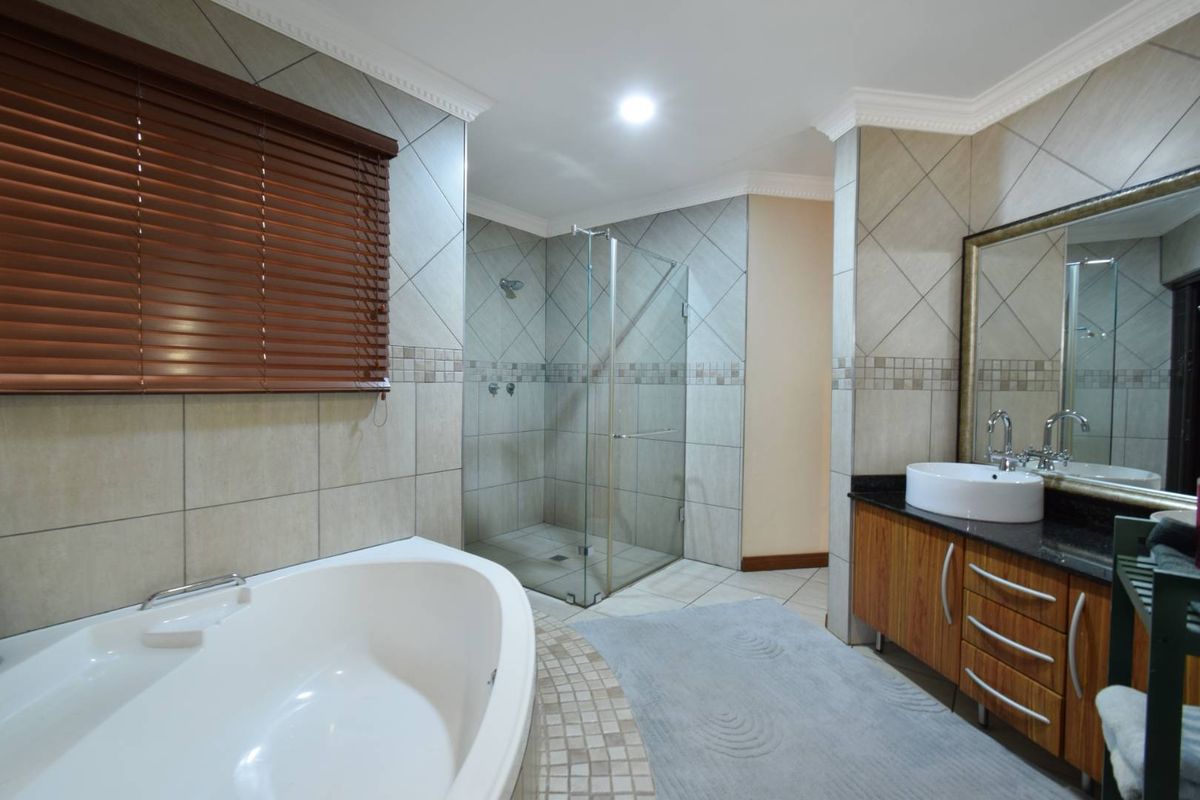 A well-appointed bathroom featuring a corner soaking tub, a glass-enclosed walk-in shower, and a vanity with a vessel sink and granite countertop.
