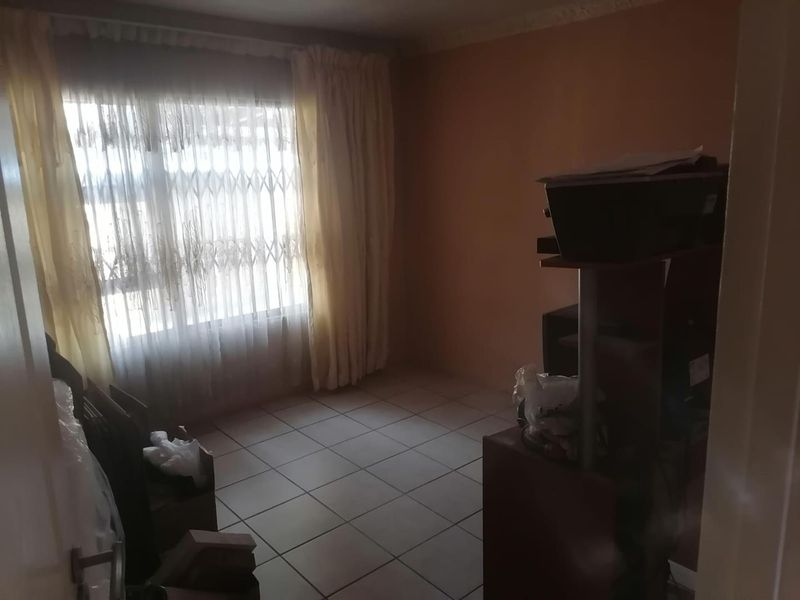 A bedroom featuring tiled flooring and a window fitted with a security gate, offering a functional space ready for personalization.