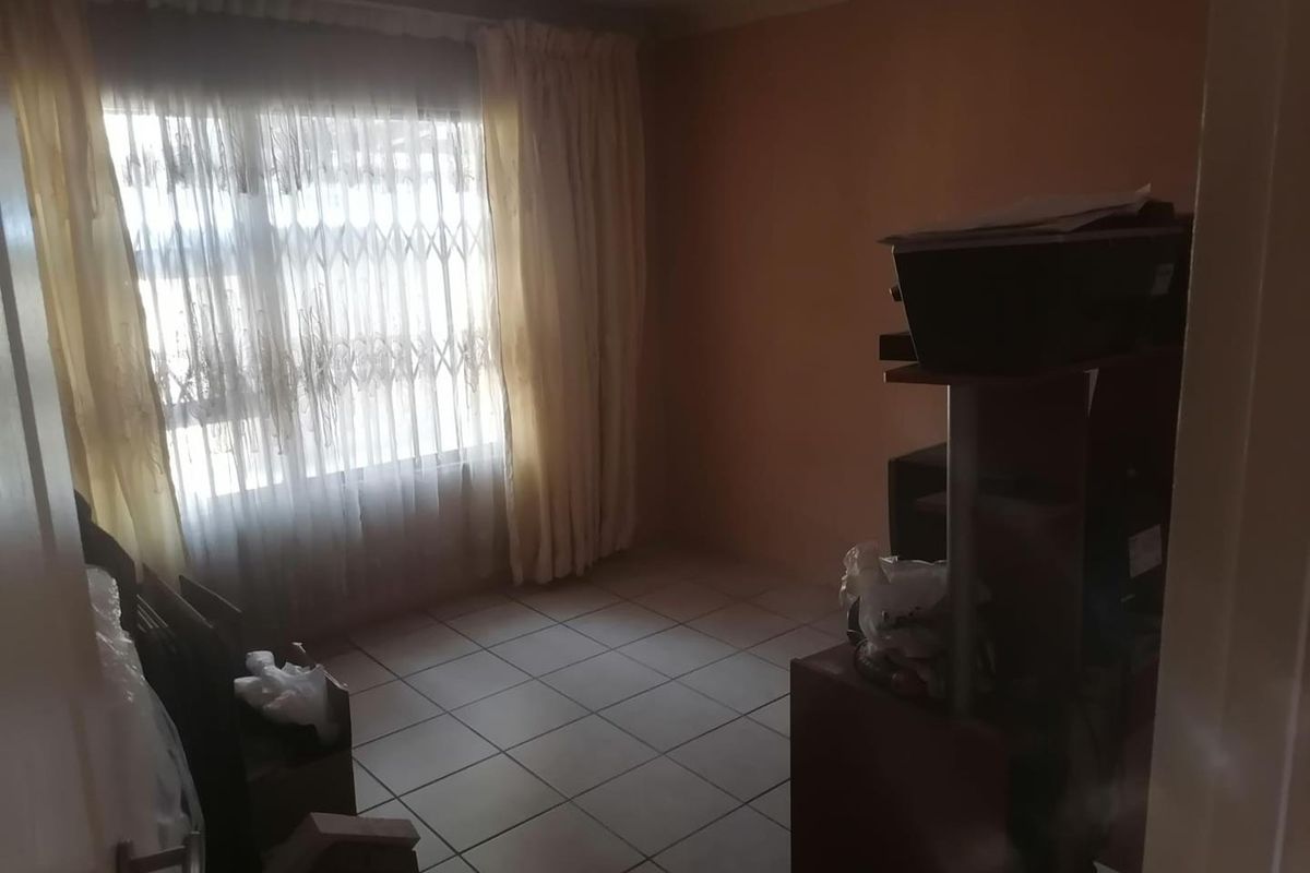 A bedroom featuring tiled flooring and a window fitted with a security gate, offering a functional space ready for personalization.