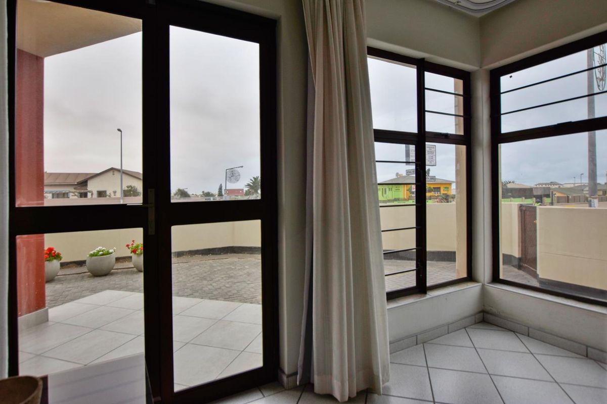 Bright living area featuring large windows and a glass door providing direct access to a paved outdoor patio space.