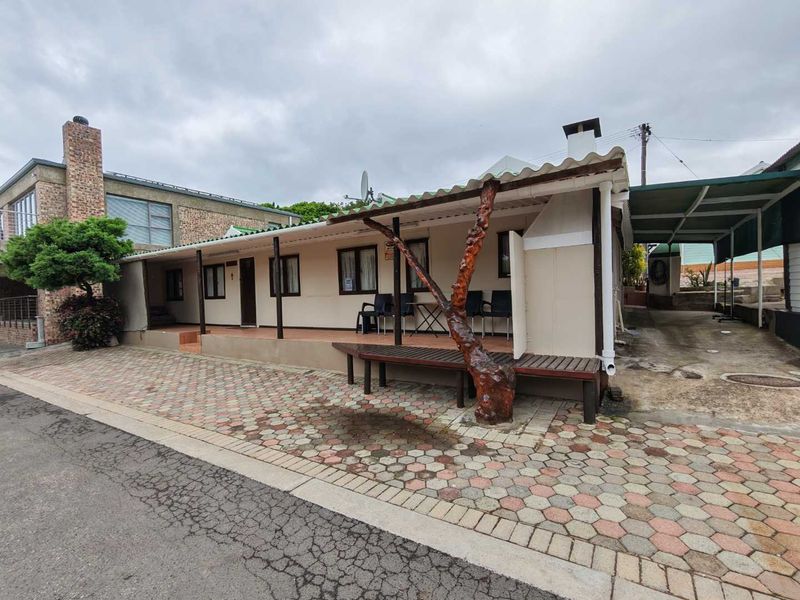Front exterior view of a single-story house featuring a covered patio, paved driveway, and attached carport area.