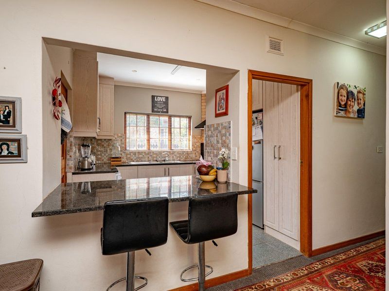 A functional kitchen featuring a granite breakfast bar, tiled backsplash, and built-in cabinetry, with an adjacent pantry area.