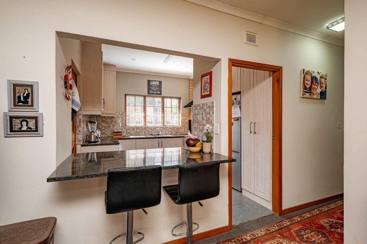 A functional kitchen featuring a granite breakfast bar, tiled backsplash, and built-in cabinetry, with an adjacent pantry area.