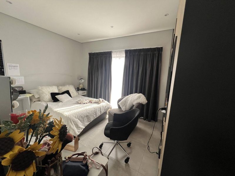 A well-maintained bedroom featuring neutral tiled flooring, recessed downlighting, and built-in cupboard storage, offering a clean and functional living space.