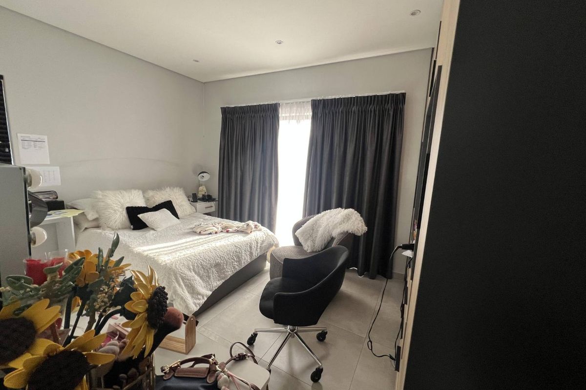 A well-maintained bedroom featuring neutral tiled flooring, recessed downlighting, and built-in cupboard storage, offering a clean and functional living space.