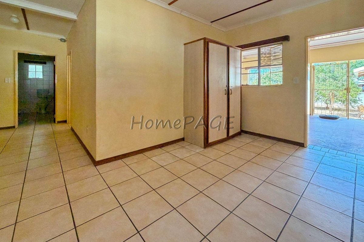 A bedroom featuring tiled flooring, a built-in cupboard, and direct access to an outdoor area through a security gate.