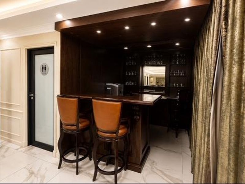 A sophisticated built-in bar area featuring dark wood cabinetry, recessed lighting, and elegant marble-look flooring, creating a refined entertainment space.