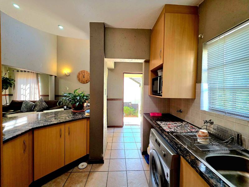 Functional kitchen featuring granite countertops, ample built-in cabinetry, and tiled flooring, with direct access to an outdoor area.