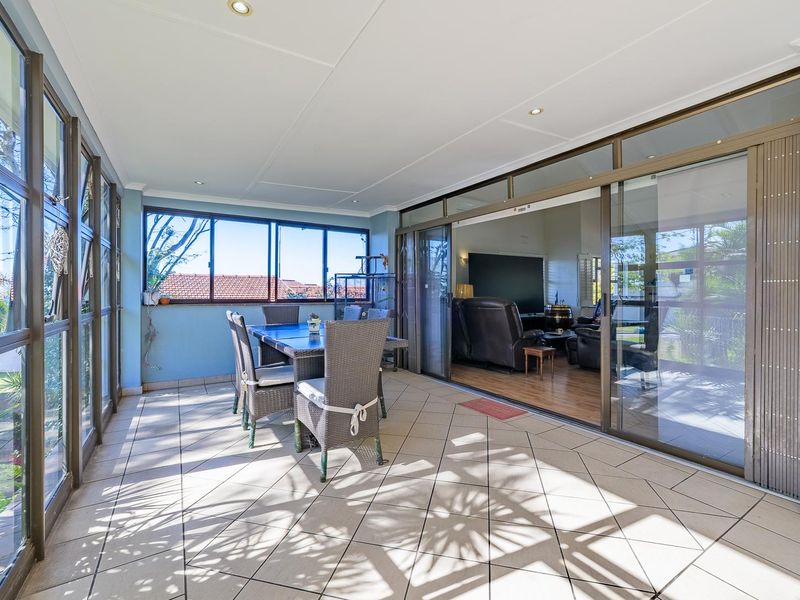A bright, enclosed patio area featuring tiled flooring and large sliding glass doors that provide seamless access to the interior living space.
