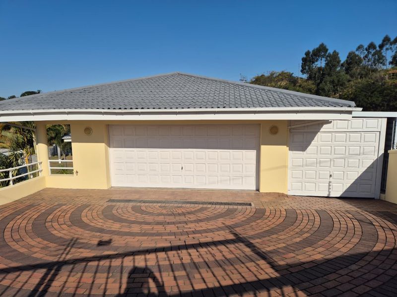 A well-maintained exterior view of a property featuring a double garage and an additional single garage with a decorative paved driveway.