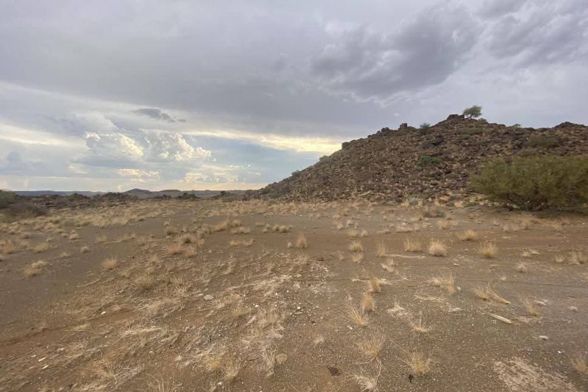 A wide-angle view of the vacant residential land featuring natural rocky terrain and open landscape under a cloudy sky.