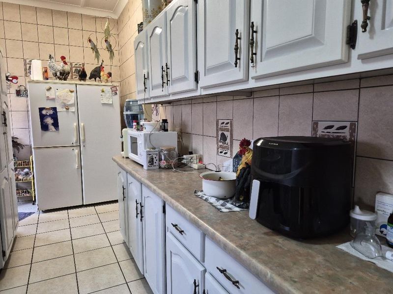 A functional kitchen featuring tiled flooring, a tiled backsplash, and ample built-in cabinetry with laminate countertops.