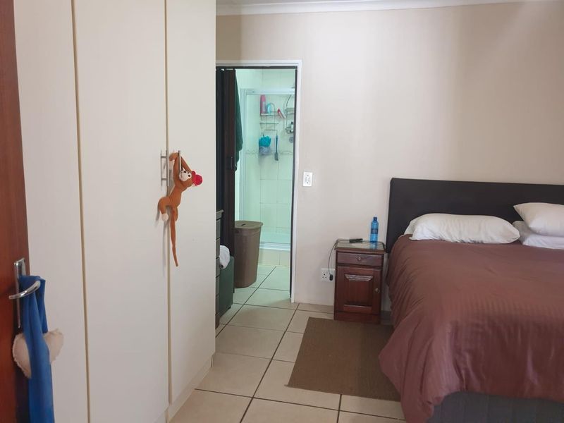 A bedroom featuring built-in cupboards, tiled flooring, and direct access to an en-suite bathroom.