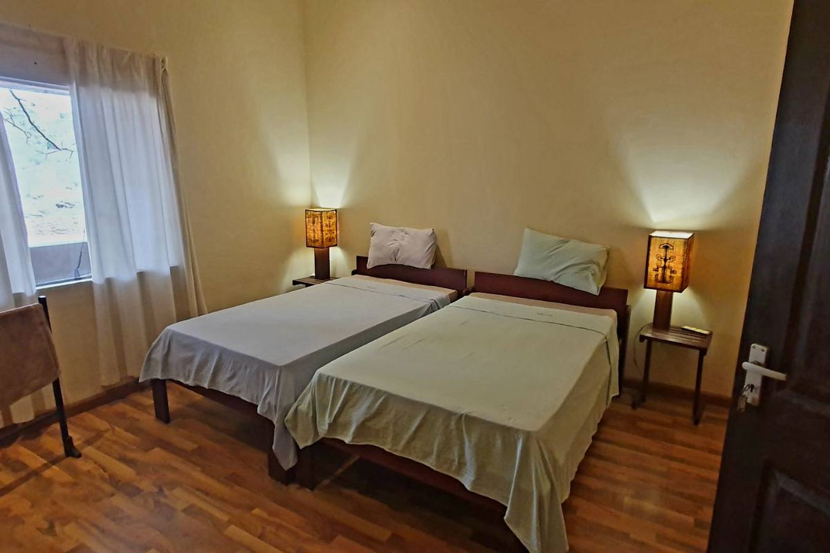 A bedroom featuring wood-look flooring and a window with curtains, providing a functional and comfortable sleeping space.