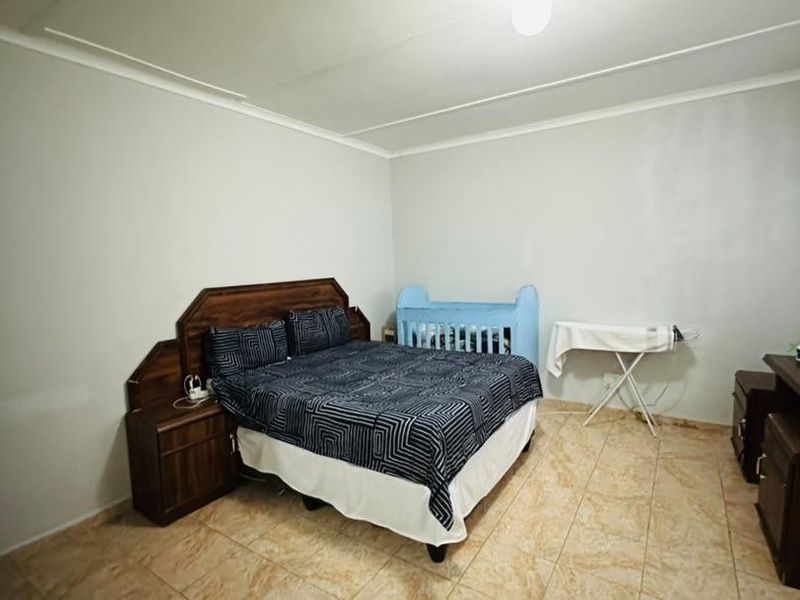 A standard bedroom featuring tiled flooring and neutral wall finishes, providing a functional space with basic architectural elements.