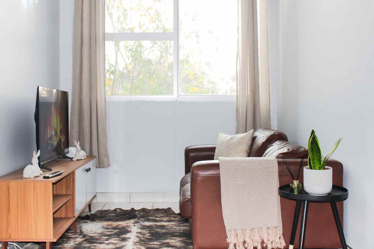 A bright and cozy living room featuring large windows that allow for ample natural light and neutral tiled flooring.