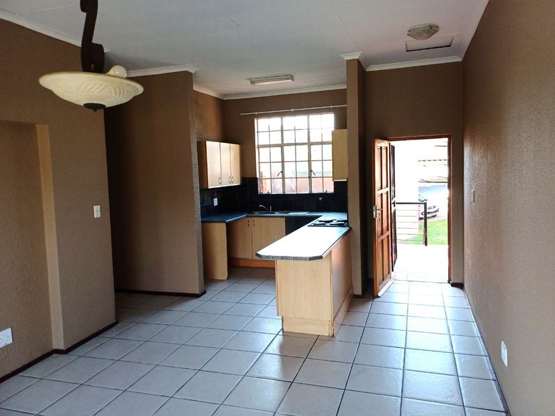 Open plan kitchen and living area featuring tiled flooring, built-in cabinetry with laminate countertops, and direct access to an outdoor space.