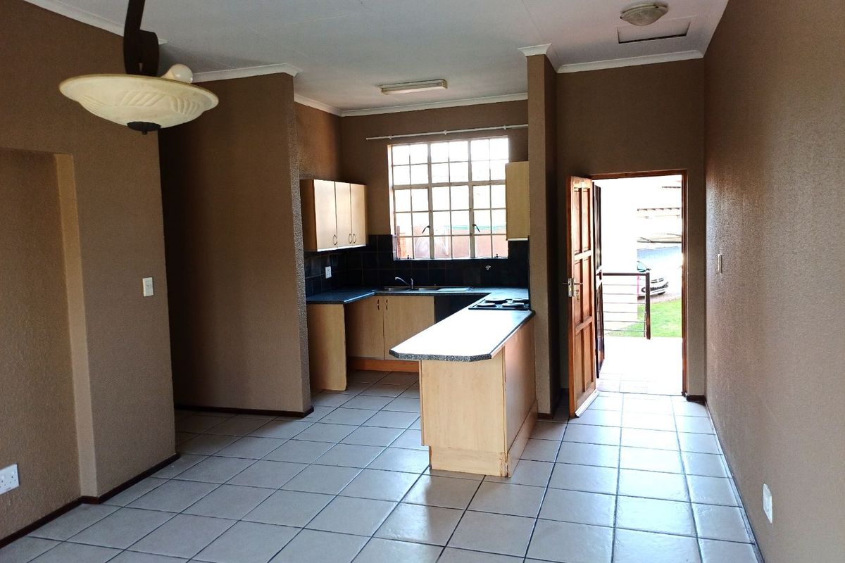 Open plan kitchen and living area featuring tiled flooring, built-in cabinetry with laminate countertops, and direct access to an outdoor space.