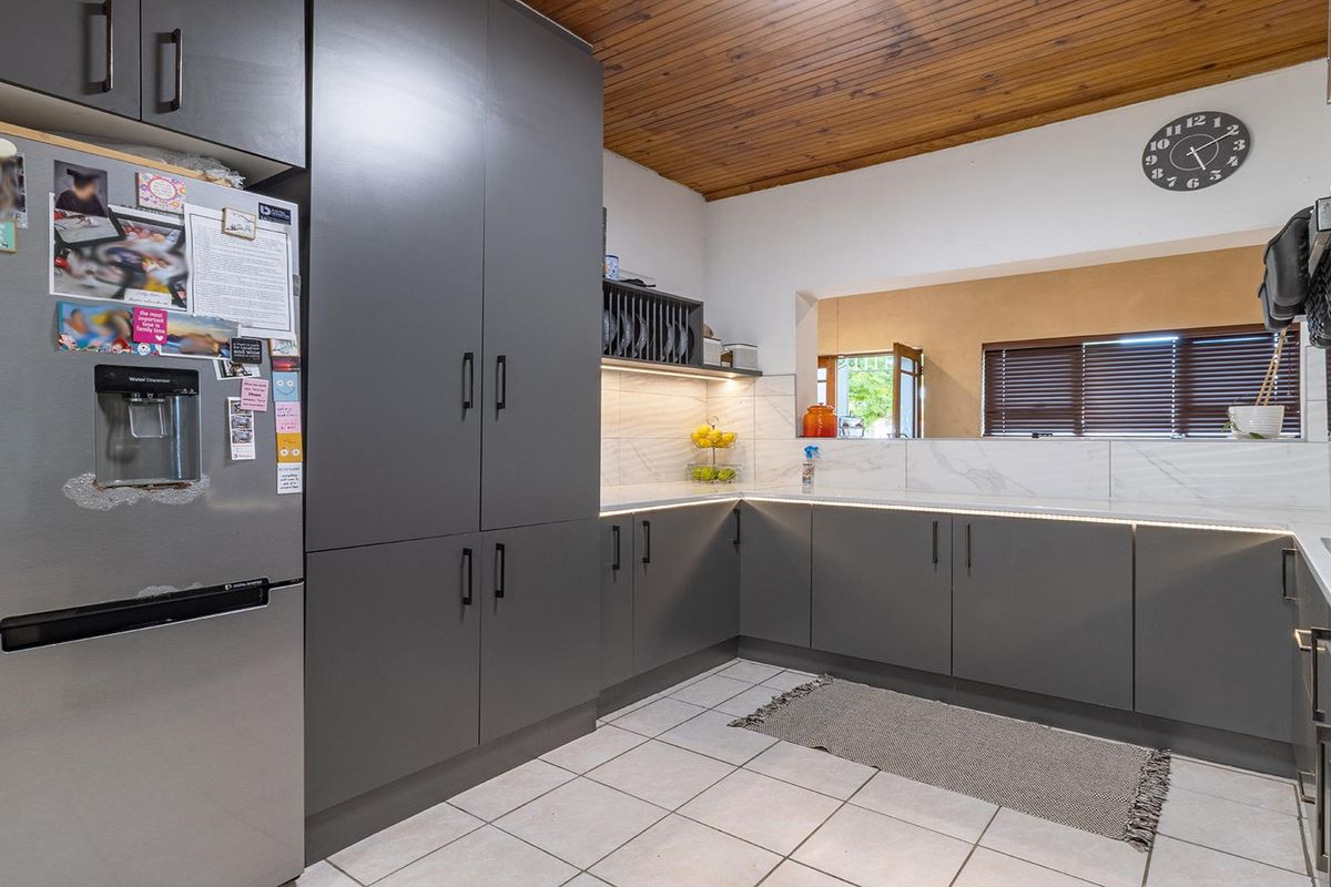 Modern kitchen featuring dark grey cabinetry, marble-look splashbacks, under-cabinet lighting, and a distinctive timber-paneled ceiling, offering a contemporary and functional workspace.