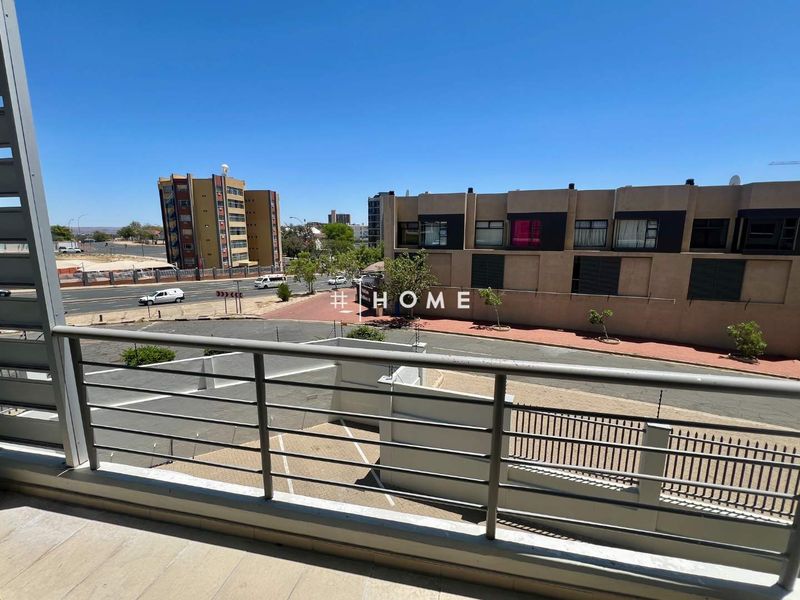 A balcony with a metal balustrade offering an elevated view of the surrounding street and neighborhood.