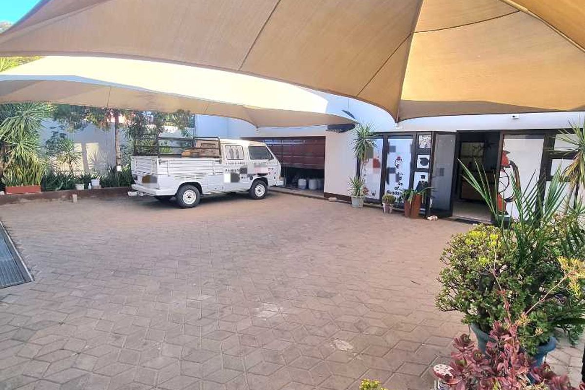 A paved outdoor courtyard area featuring large overhead shade sails and access to the building interior via sliding glass doors.
