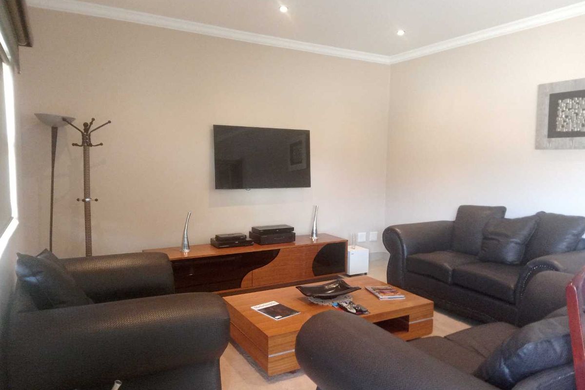 A comfortable living room featuring recessed downlighting, coved ceiling details, and a wall-mounted television setup.