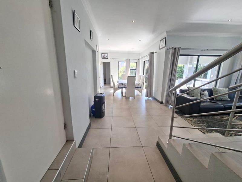 Spacious open-plan living and dining area featuring neutral tiled flooring, recessed lighting, and direct access to the outdoor patio through sliding glass doors.
