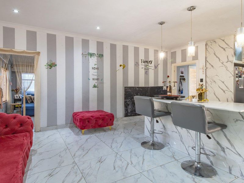 Open-plan living and kitchen area featuring marble-look tiled flooring, a matching marble-look kitchen island, and modern pendant lighting.