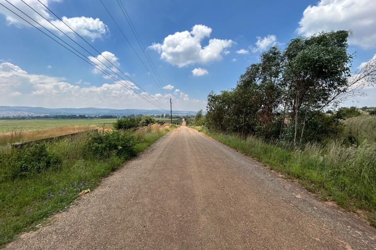 A view of the gravel access road leading through the farm property, featuring surrounding open fields and natural landscape.