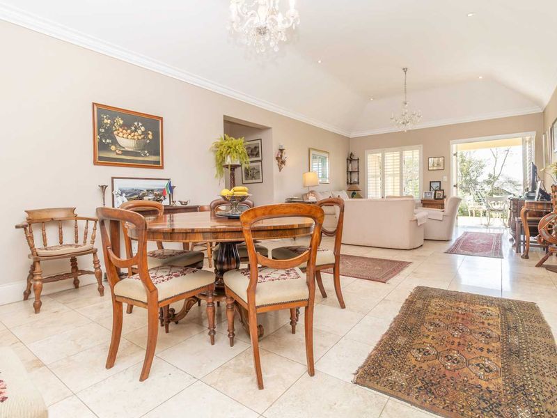 Spacious open-plan living and dining area featuring vaulted ceilings, tiled flooring, elegant chandeliers, and large sliding doors providing access to the outdoor space.