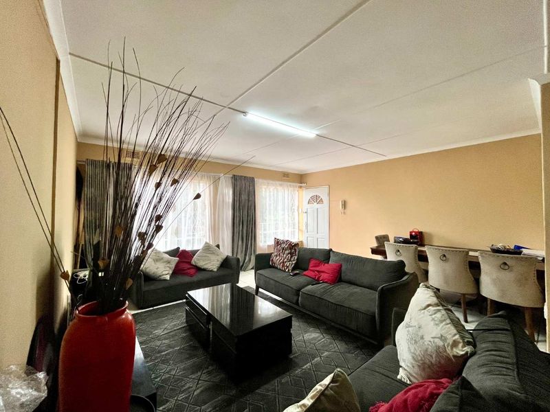 A spacious living area featuring tiled flooring, neutral wall tones, and a functional layout with direct access to the entrance.