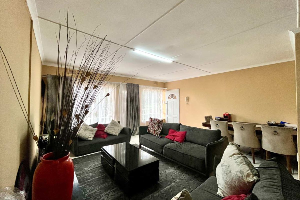 A spacious living area featuring tiled flooring, neutral wall tones, and a functional layout with direct access to the entrance.