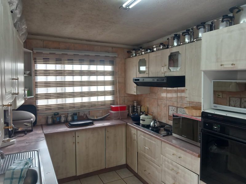 A functional kitchen featuring built-in cabinetry, laminate countertops, a built-in oven, hob, and extractor fan with tiled backsplash and neutral flooring.