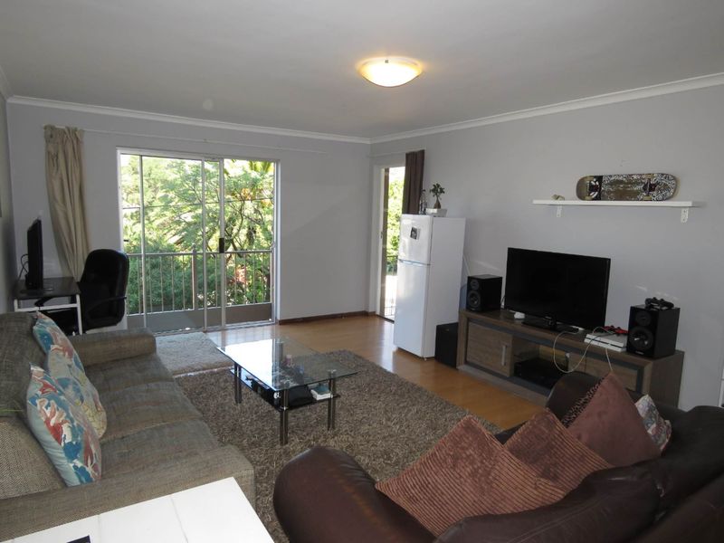 Spacious living room featuring laminate flooring, neutral walls, and a sliding glass door providing access to an outdoor balcony area.
