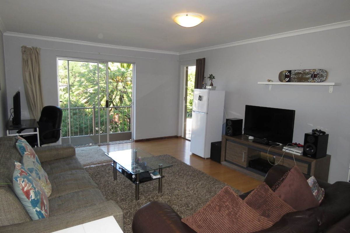 Spacious living room featuring laminate flooring, neutral walls, and a sliding glass door providing access to an outdoor balcony area.