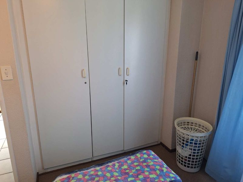 A bedroom featuring functional built-in cupboards with white doors, providing essential storage space within the room.