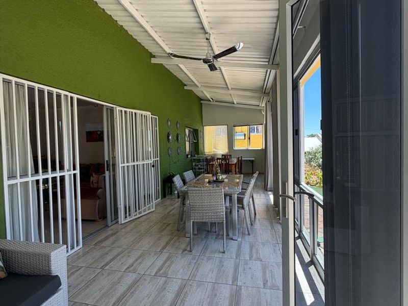 A spacious covered patio featuring tiled flooring, a ceiling fan, and secure sliding door access to the main living area.