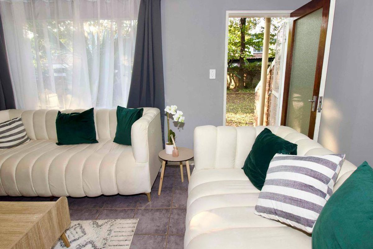 A living room featuring tiled flooring and direct access to an outdoor area through a glass-paneled door.