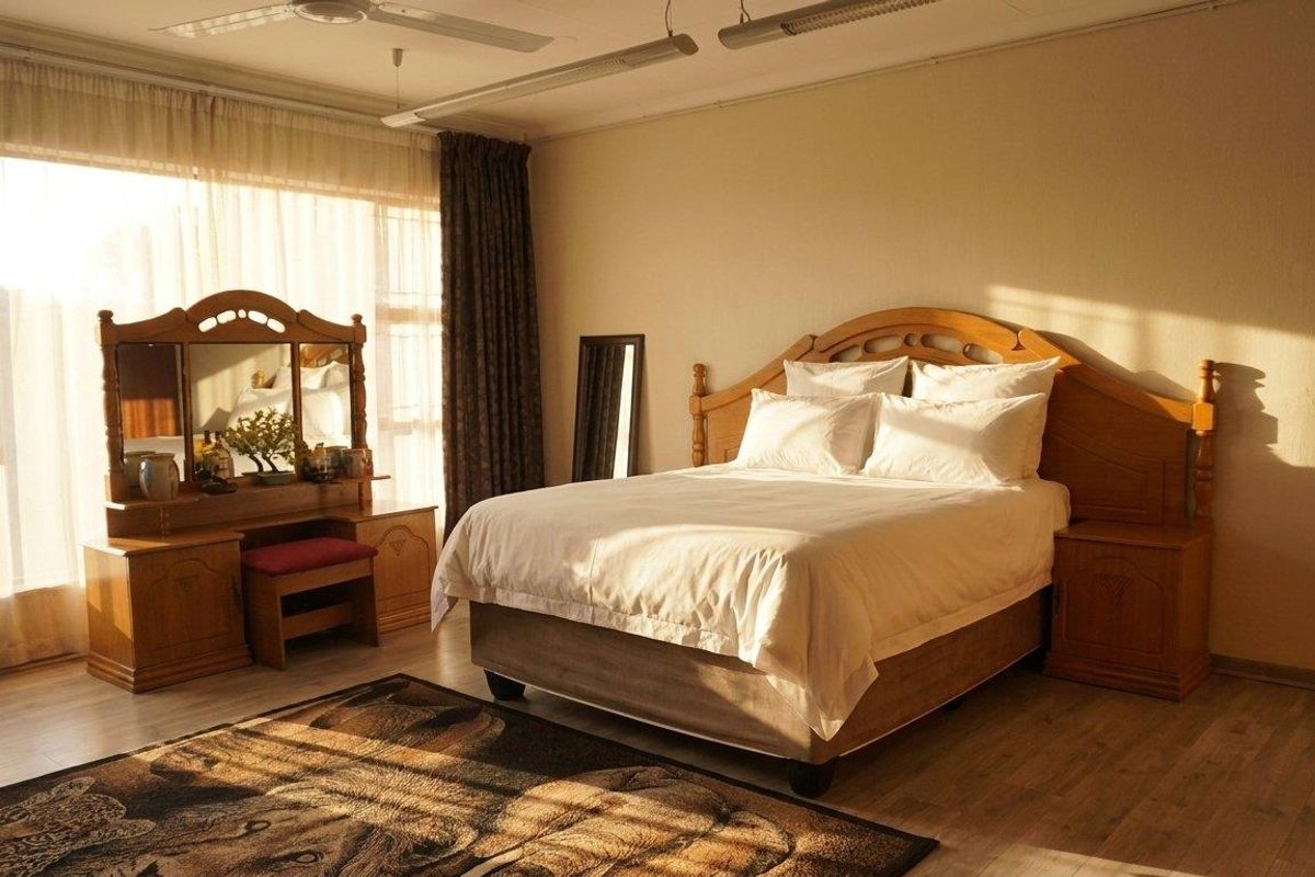 A spacious bedroom featuring light-toned laminate flooring, large windows with natural light, and a ceiling fan.