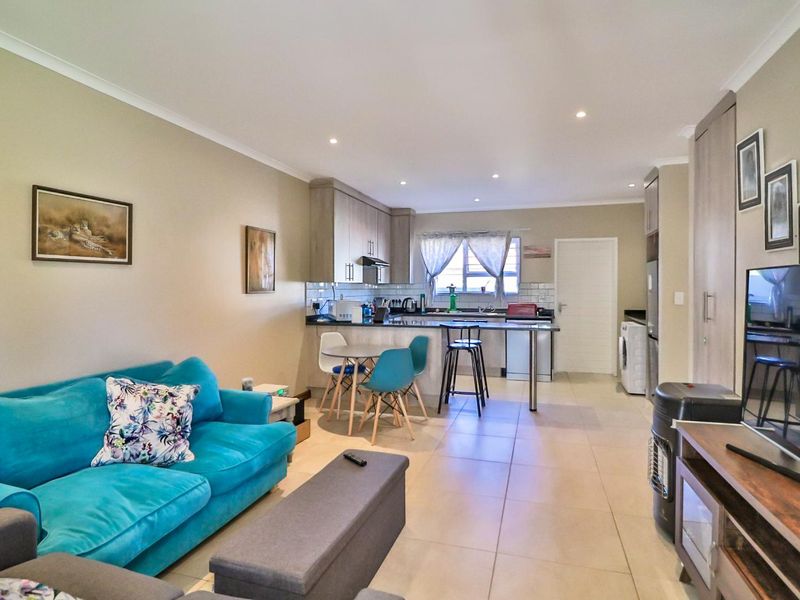 Open plan living area featuring a modern kitchen with built-in cabinetry, breakfast bar, and tiled flooring throughout the combined space.
