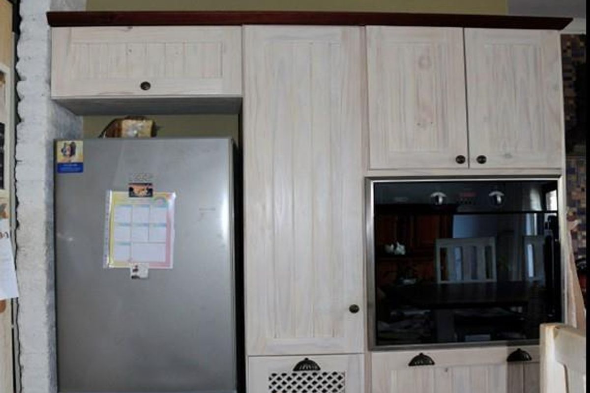 A kitchen wall featuring built-in cabinetry with a light wood finish, integrated oven, and space for a refrigerator.