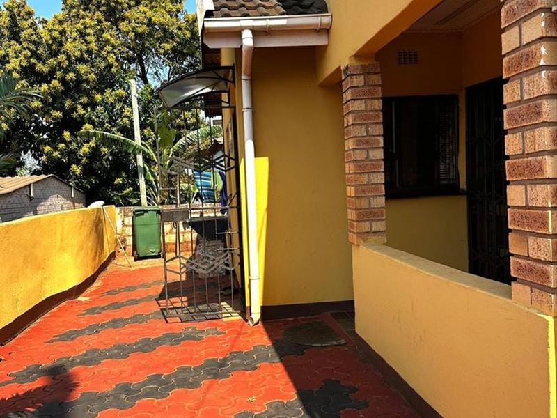 A covered patio area featuring brick pillars and paved flooring, providing an outdoor space for relaxation.