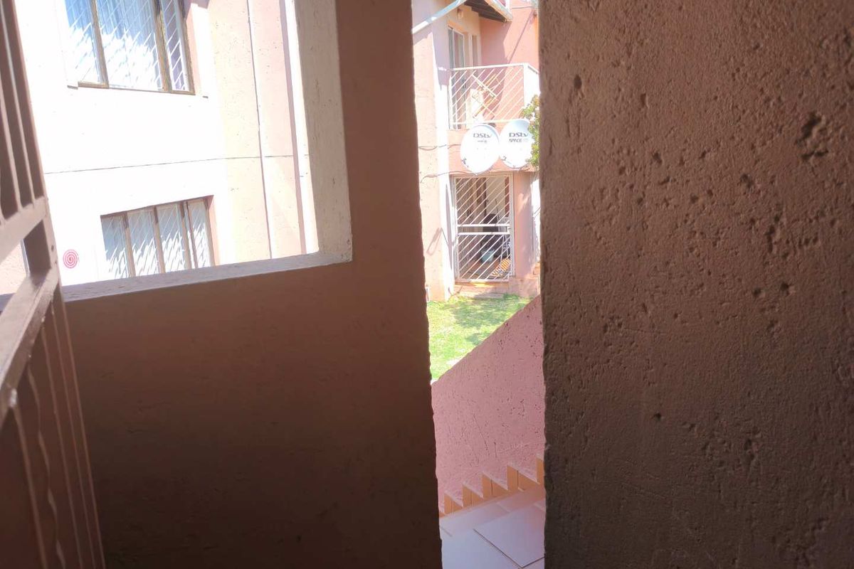 View from a covered walkway looking out towards the rear courtyard area of the townhouse complex.