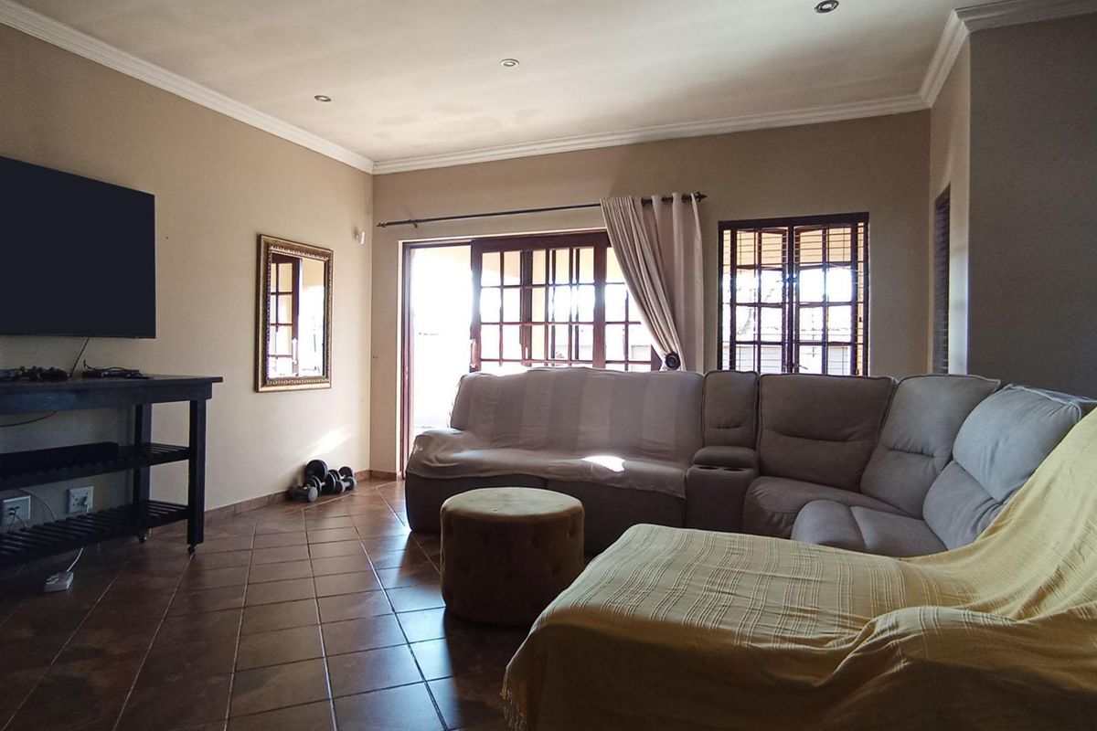 A spacious living room featuring tiled flooring, recessed ceiling lighting, and sliding glass doors providing access to the outdoor area.